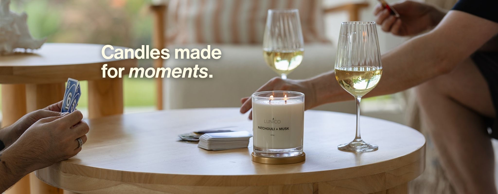 Lunico Candle Co. - Candle and wine glasses on a table with 'Candles made for moments' text.