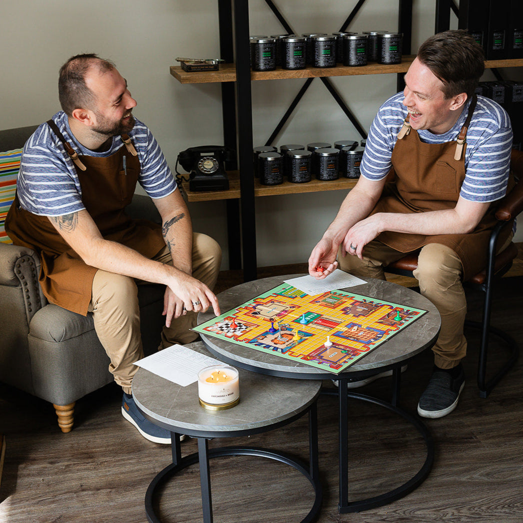 William and Jacob are playing Cluedo in the candle shop. They are in uniform and laughing at each other.